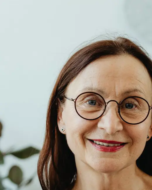 Dana Sobczak, founder of Stackly, a smiling woman with auburn hair and round glasses in a black top.